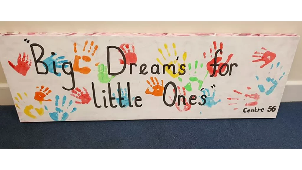A canvas reading 'Big dreams for little one's' decorated with children's hand prints