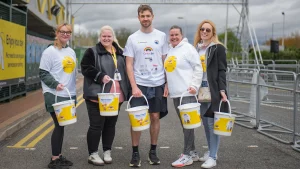 A group of volunteers stand holding collection buckets